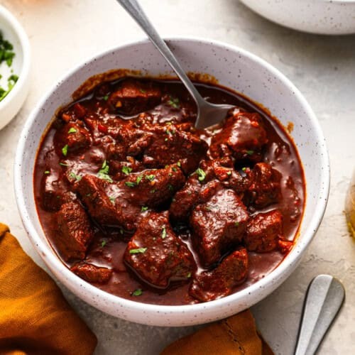 close-up of rich, saucy chili-pepper beef roast with steam, comfort food served in a rustic bowl
