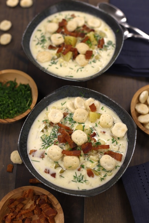 rustic bowl of creamy potato chowder with crusty bread on a wooden table, cozy lighting