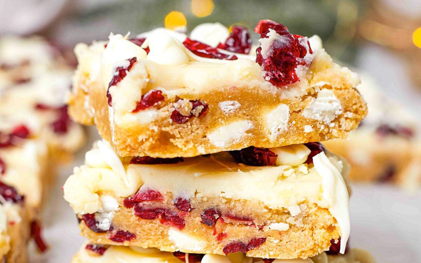 Vibrant cranberry bliss bars with white chocolate swirl on a cooling rack, festive kitchen background