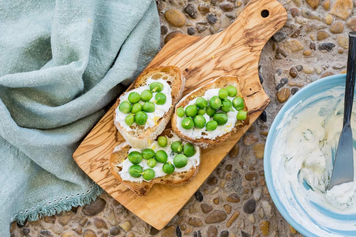vibrant spring ricotta pea radish crostini on wooden board
