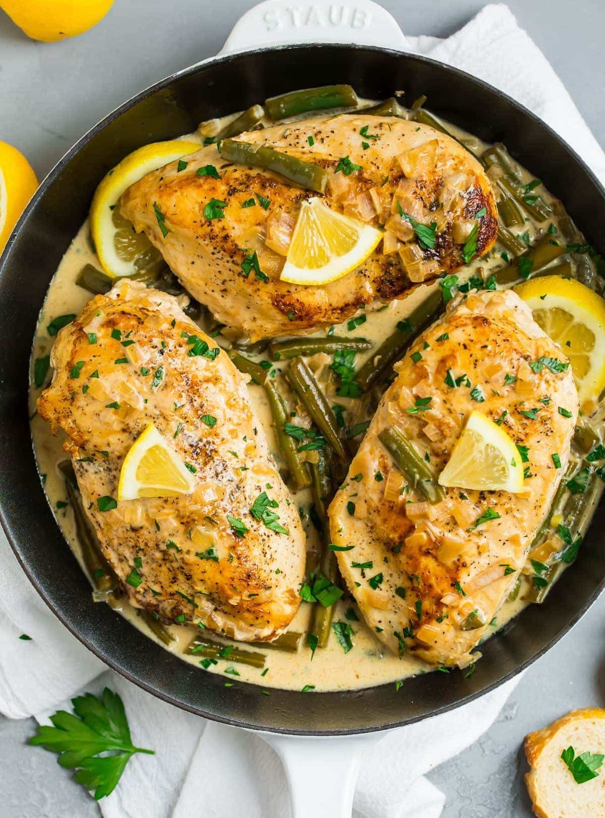 lemon butter chicken breast sizzling in a pan with herbs