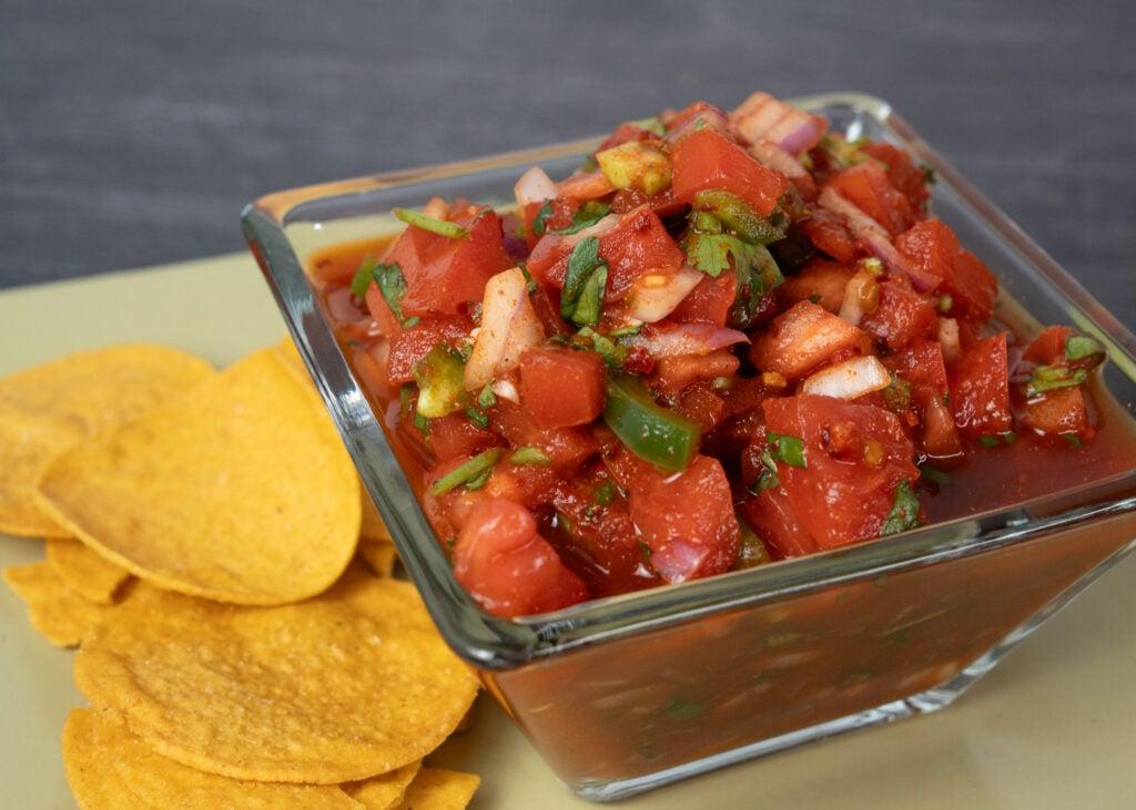 freshly made chili lime rhubarb salsa in a glass bowl with tortilla chips