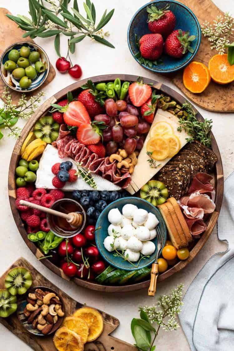 arrangement of cheese, crackers, and fruit slices on a wooden board