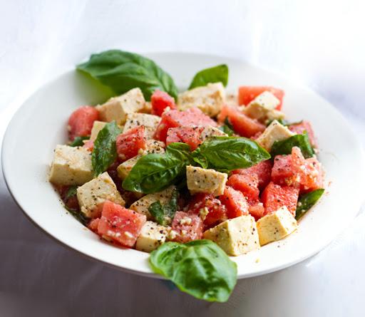 Watermelon and balsamic glazed tofu served on a white plate with basil garnish