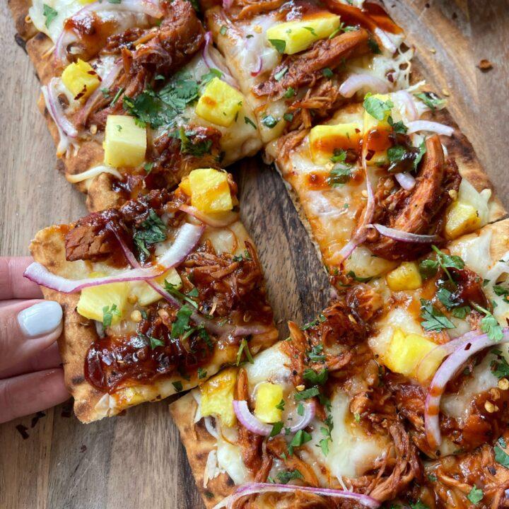 grilled chicken and pineapple pizza on a wooden board