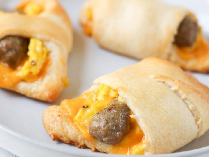 Close-up of golden crescent roll ups filled with sausage and scrambled eggs on a rustic breakfast table