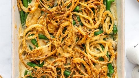 creamy soft texture green bean casserole with crispy fried onions on top, a spoonful being lifted, warm and inviting atmosphere