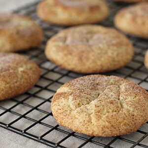 freshly baked snickerdoodle cookies on a cooling rack, dusted with cinnamon sugar